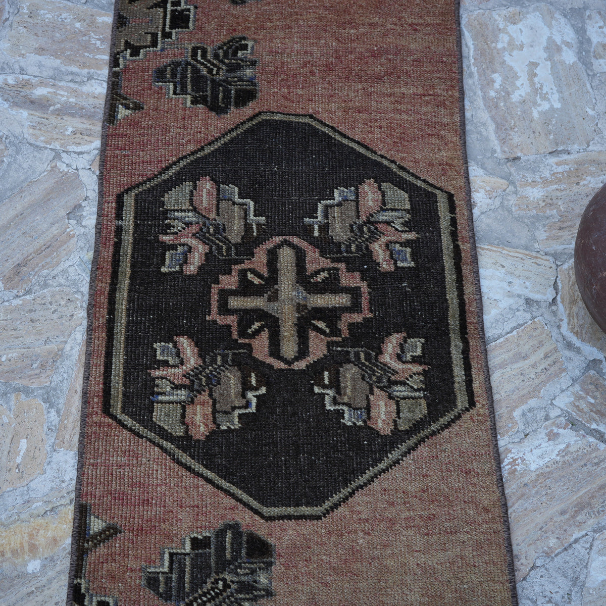 Close-up of the pale red vintage turkish runner rug showing traditional details, hand-knotted weave, wool and cotton and low pile.