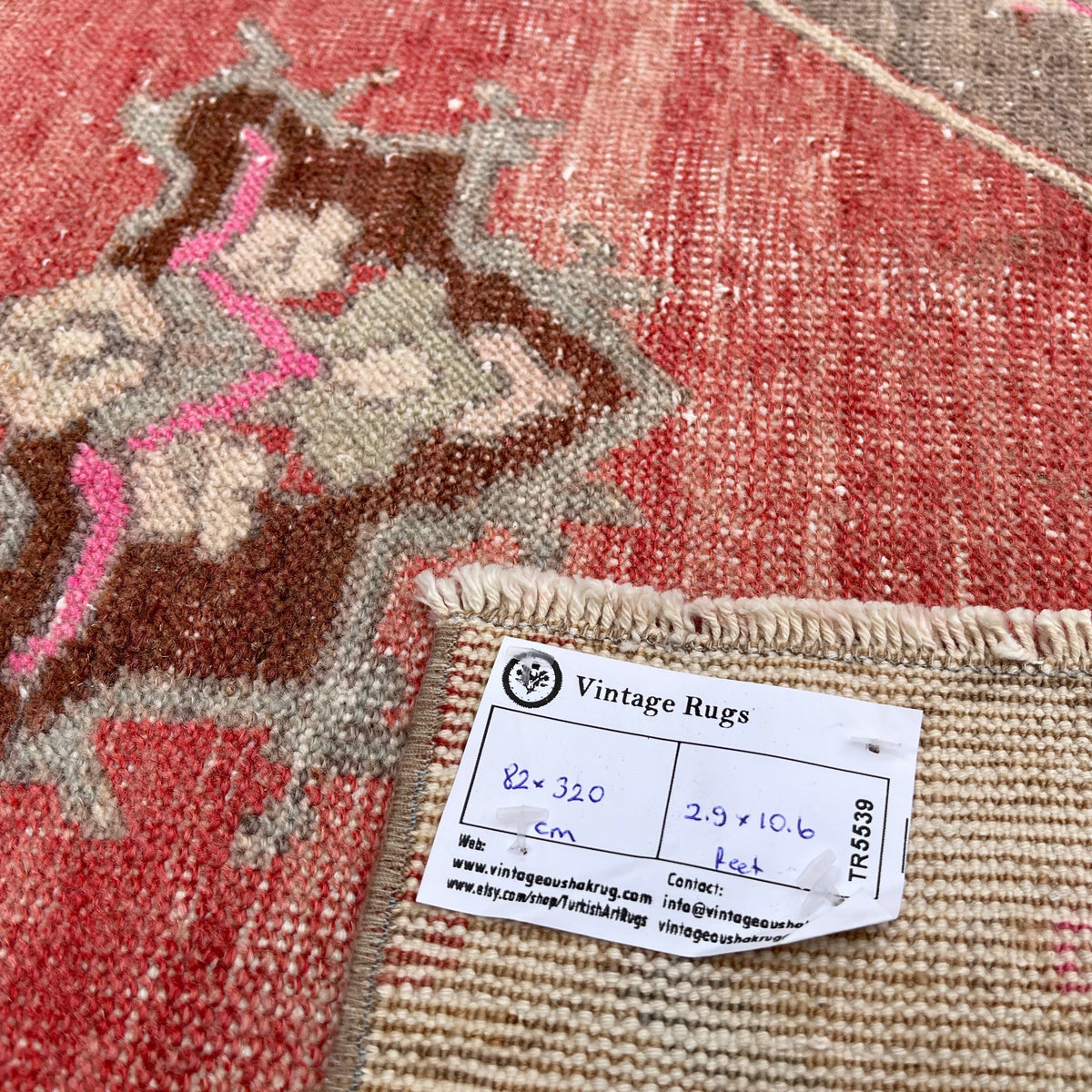 Close-up of the pale red vintage turkish runner rug showing traditional details, hand-knotted weave, wool and cotton and low pile.