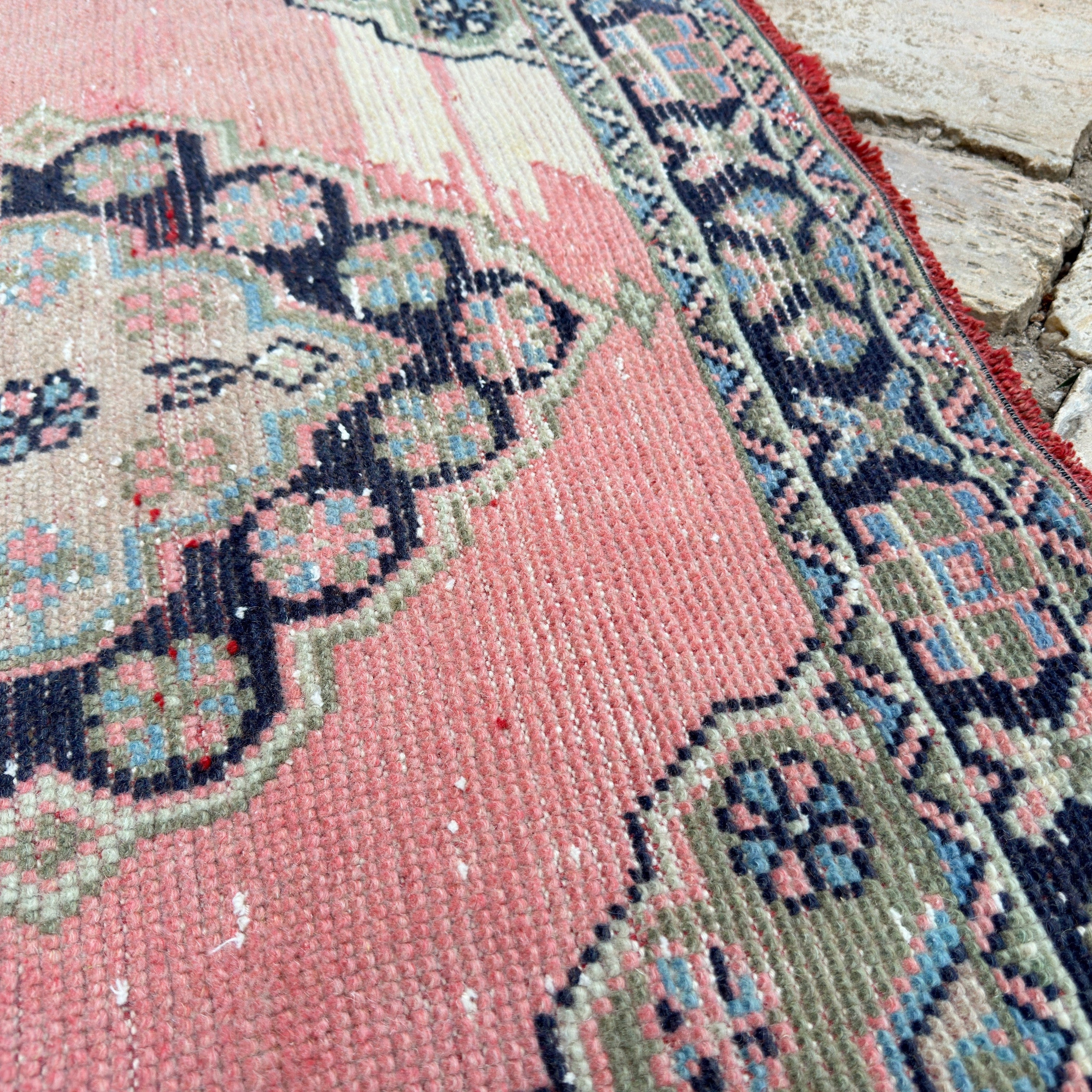 Close-up of the pink vintage turkish runner rug showing traditional details, hand-knotted weave, wool and cotton and low pile.