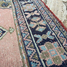 Close-up of the pink vintage turkish runner rug showing traditional details, hand-knotted weave, wool and cotton and low pile.