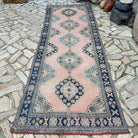 Pink 4' x 11' vintage turkish runner rug in wool and cotton, shown on the floor.
