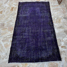 Close-up of the purple vintage Turkish wool overdyed rug showing overdyed details, hand-knotted weave, wool and cotton and low pile.