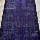 Purple 4' x 7' vintage Turkish wool overdyed rug in wool and cotton, shown on the floor.