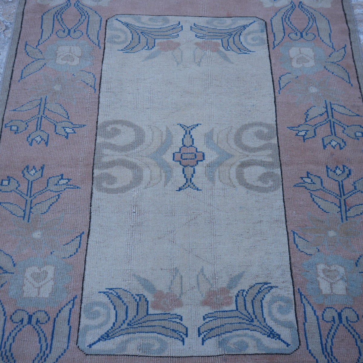 Close-up of the pink vintage Turkish wool rug showing geometric details, hand-knotted weave, wool and low pile.