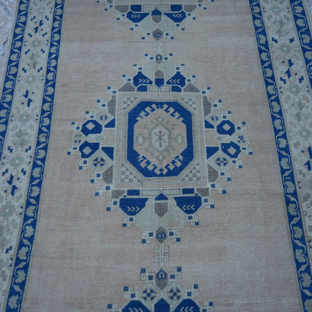 Close-up of the pale pink vintage Turkish wool rug showing traditional details, hand-knotted weave, wool and low pile.