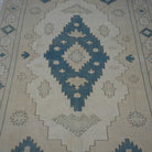 Close-up of the beige vintage Turkish wool rug showing neutral and geometric details, hand-knotted weave, wool and low pile.