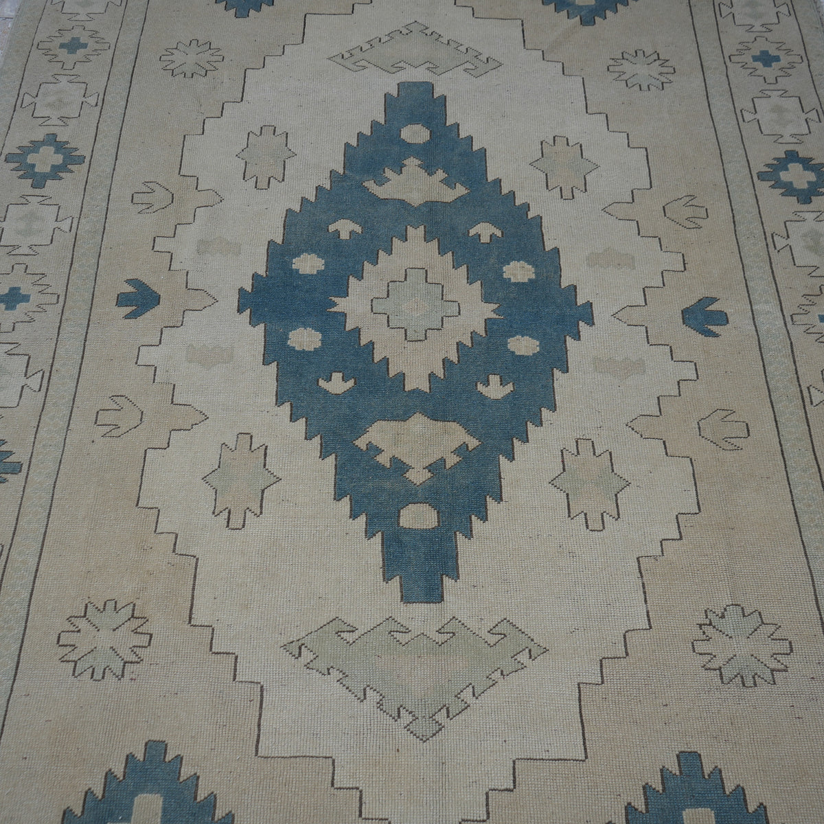 Close-up of the beige vintage Turkish wool rug showing neutral and geometric details, hand-knotted weave, wool and low pile.
