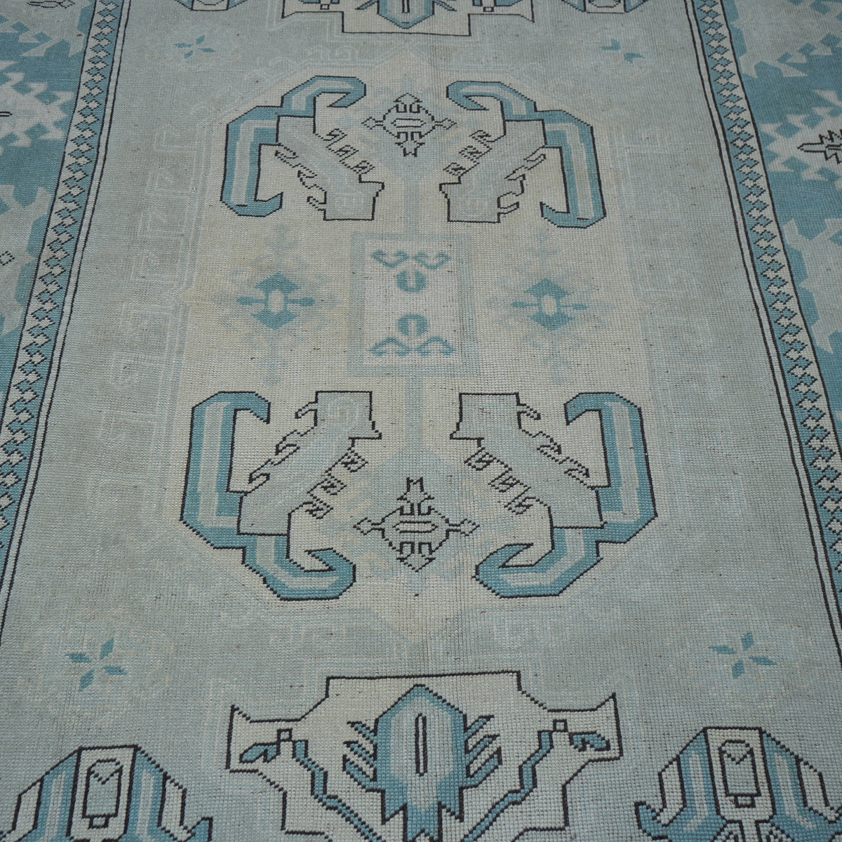 Close-up of the pale blue vintage Turkish wool rug showing geometric details, hand-knotted weave, wool and low pile.