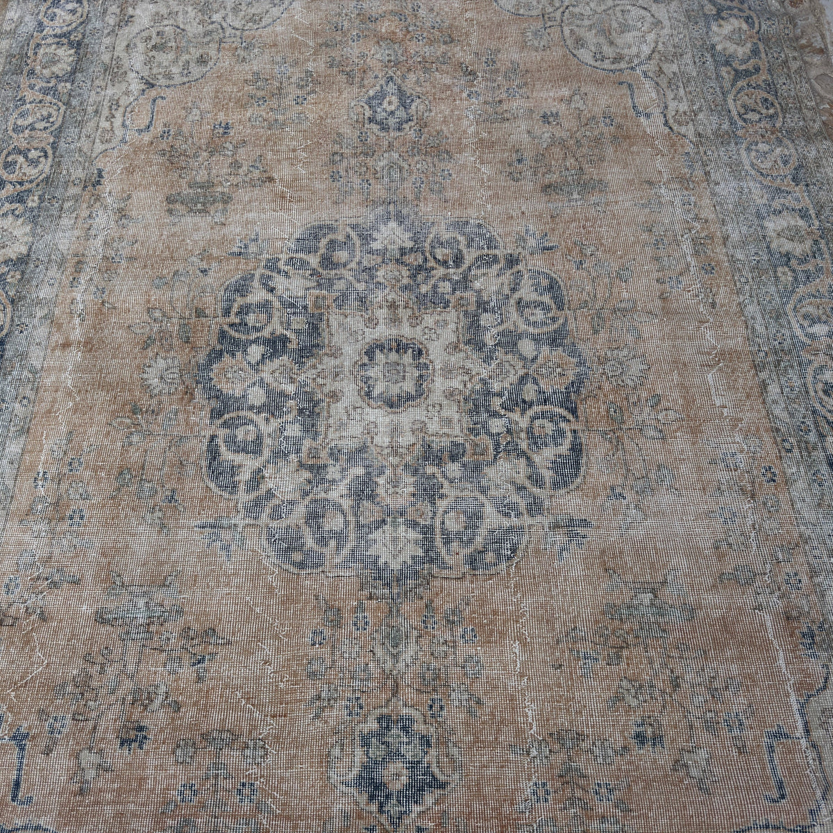 Orange 7' x 11' vintage Turkish wool rug in wool and cotton, shown on the floor.