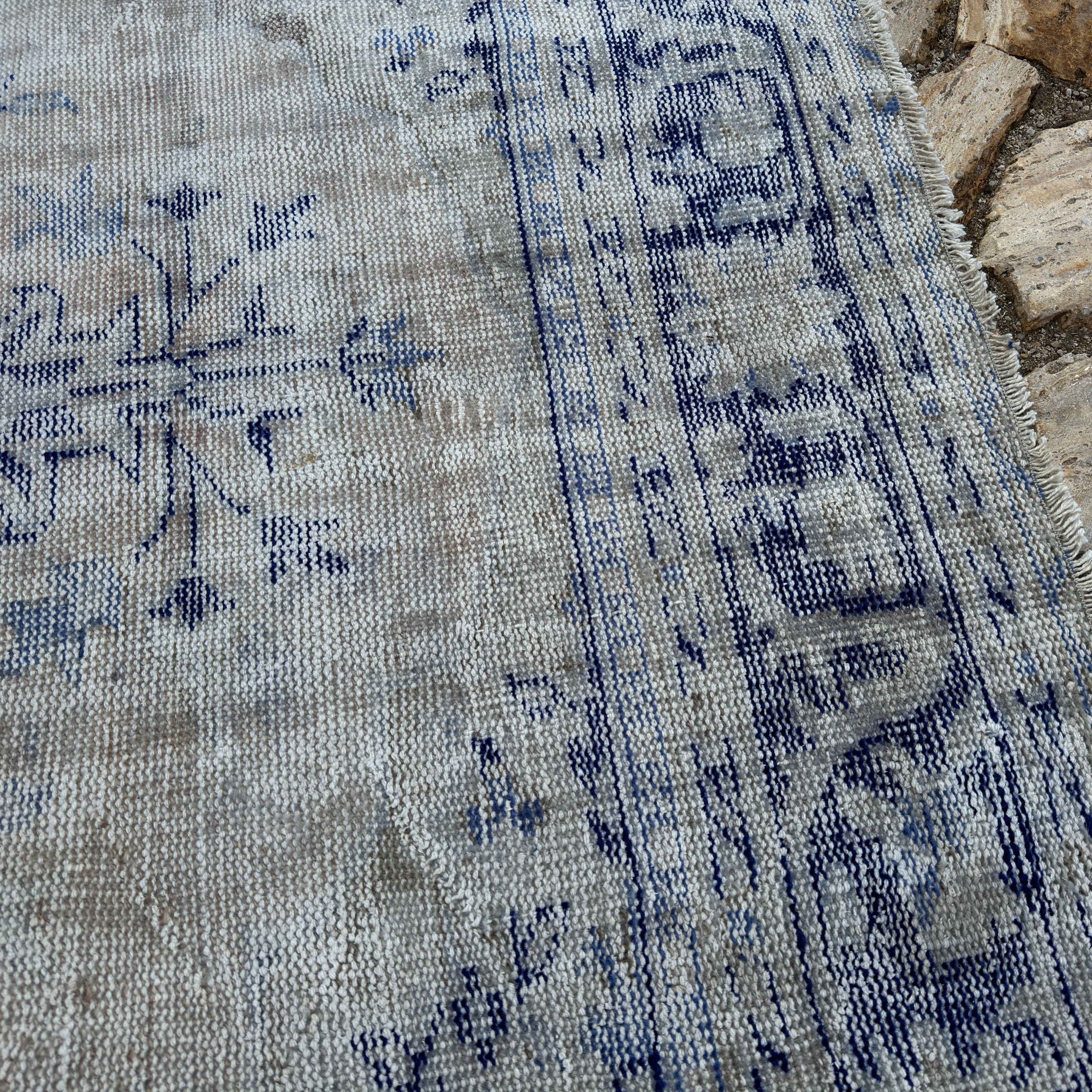 Close-up of the pale blue Turkish wool distressed carpet showing medallion details, hand-knotted weave, wool and cotton and low pile.