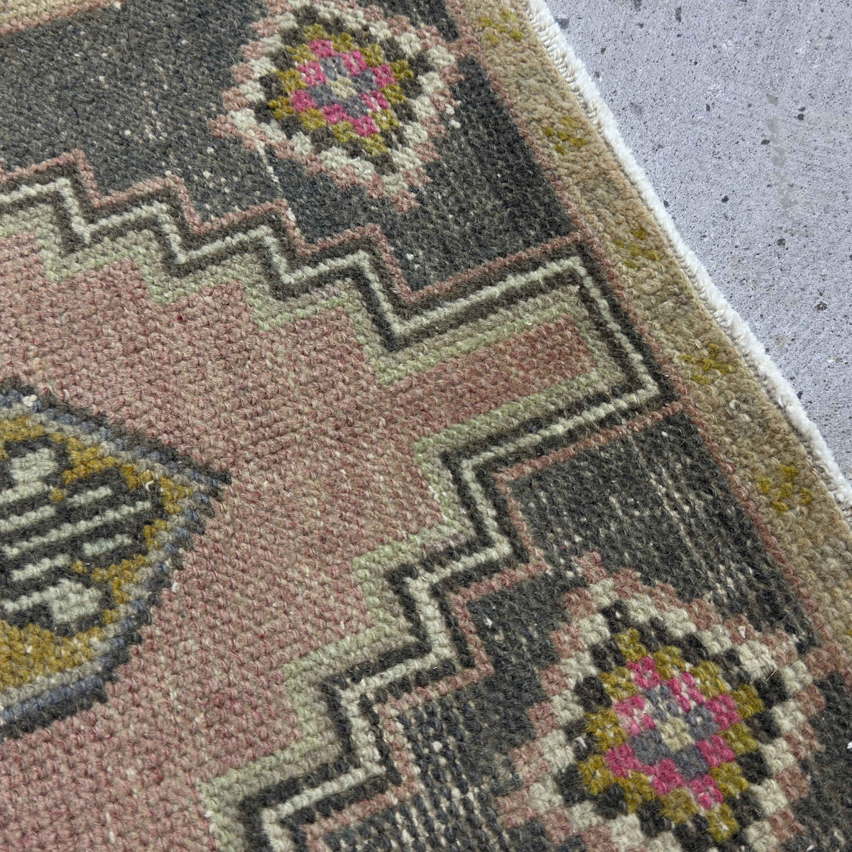 Close-up of the pale pink Turkish wool vintage rug showing traditional details, hand-knotted weave, wool and cotton and low pile.